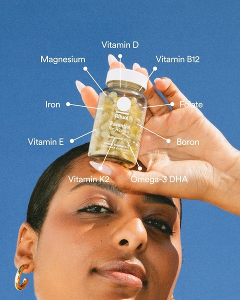 A close-up shot of a model holding a bottle of multivitamin capsules with clear, thin-line callouts identifying each key nutrient.